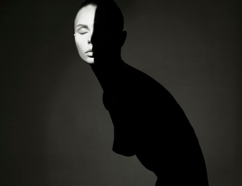 Ritratto in bianco e nero di una figura femminile metà in luce e metà in ombra, simbolo di dualità interiore, silenzio e introspezione emotiva.