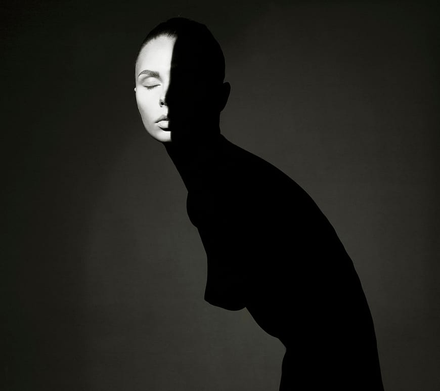 Ritratto in bianco e nero di una figura femminile metà in luce e metà in ombra, simbolo di dualità interiore, silenzio e introspezione emotiva.